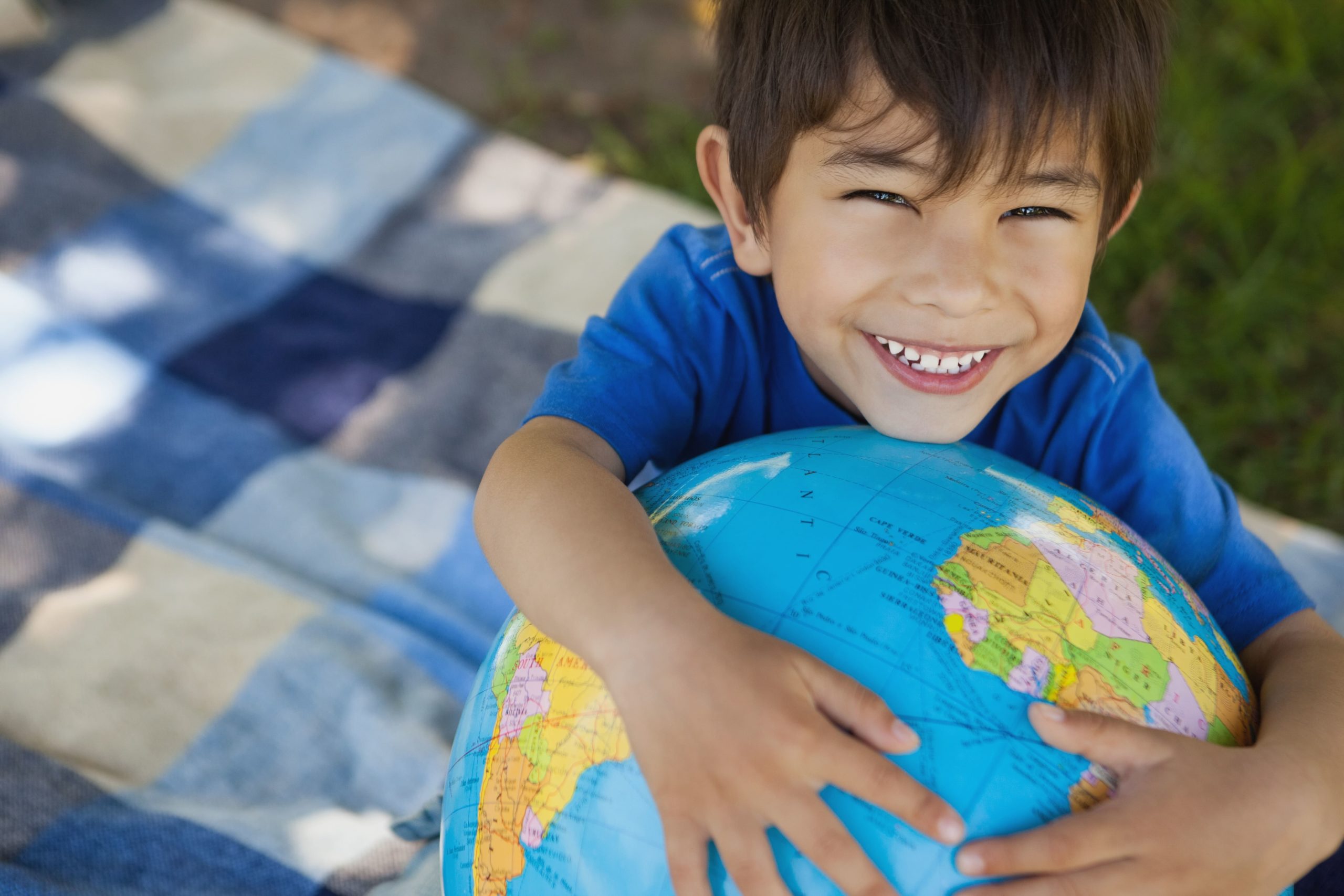young boy holding globe smiling